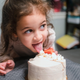 little girl sneaking lick of cake